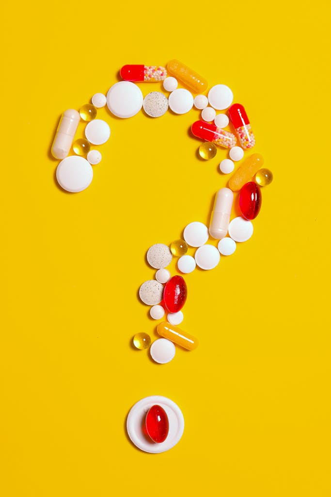 photo by anna shvets A creative arrangement of various pills forming a question mark against a bright yellow background.