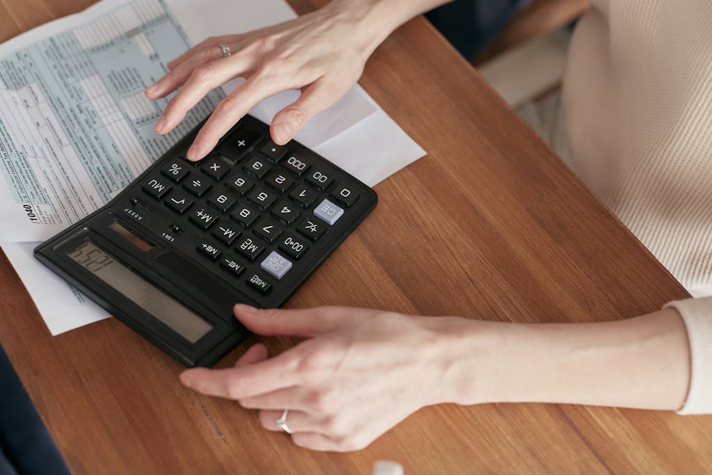 photo by mikhail nilov Close-up of a woman using a calculator and reviewing bills at home.